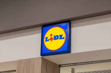 Poznan, Polonya - 15 Mart 2025: Alışveriş merkezinin içindeki duvarda ışıklı sarı ve mavi logo işareti bulunan Lidl süpermarket girişi, uygun fiyatlı market perakende zincirini temsil ediyor