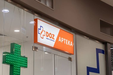Poznan, Polonya - 15 Mart 2025: DOZ eczane vitrininde açık tabela ve yeşil LED haç sembolü, cam kapılar ve temiz iç tasarım