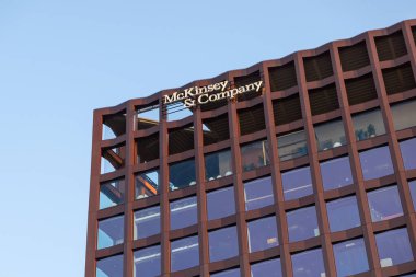 Poznan, Polonya - 15 Mart 2025: Açık mavi gökyüzü altında büyük cam pencereler ve geometrik tasarım içeren McKinsey & Company logosu en üst katta yer alan modern ofis binası