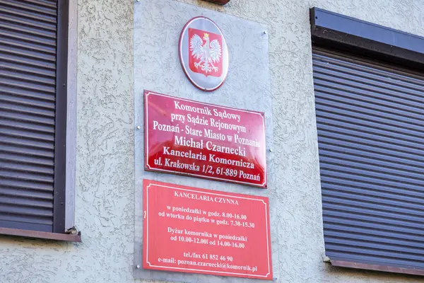Poznan, Polonya - 15 Mart 2025: Polonya Adliyesi icra memuru imzalı kırmızı plaka ve beyaz kartal amblemi ile Poznan 'da temas ve çalışma saatlerini gösteren hukuk bürosu