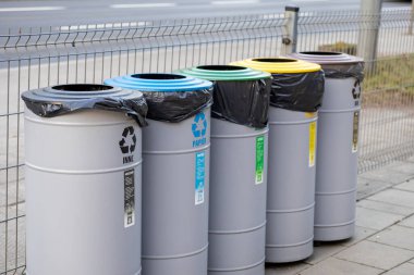 Şehir kaldırımında kağıt, plastik, metal, cam ve karışık atık için renkli geri dönüşüm kutularının sıralanması, organize atık ayrımı ve çevre bilincinin teşvik edilmesi