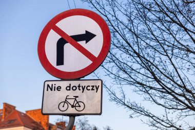 Gün batımında arka planda ağaç dalları ve çatılarla yakalanan bisikletleri saymazsak sağa dönüş işareti yok.