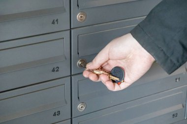 Konut binasının lobisindeki posta kutusunun kilidini açan anahtarlarla birlikte anahtar deliği ve posta yuvalarının yakın görüntüsü