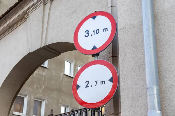 Avrupa 'da kemer yolunun yanındaki bej bina duvarında boy ve genişlik kısıtlaması işaretleri, araçlar için geçiş limitlerini belirtiyor