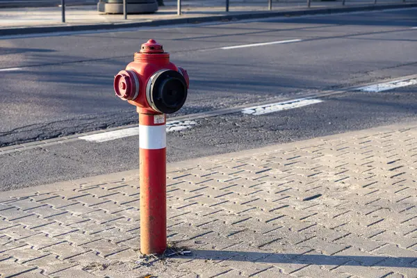Güneşli bir günde şehir sokağının yakınındaki kaldırımda kırmızı yangın musluğu kaldırım deseni ve kamu güvenliği ve acil durum erişim kavramı için boş yol arkaplanı.