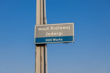 Poznan 'daki Kraliçe Jadwiga Köprüsü tabelasında, güneşli bir günde açık mavi gökyüzüne karşı Warta Nehri etiketi var.