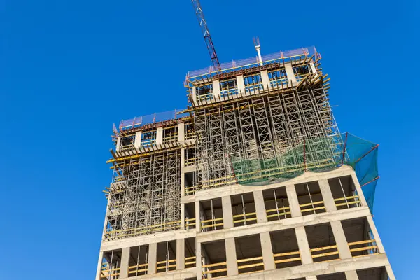 Gündüz kentsel gelişim sürecinde berrak mavi gökyüzüne karşı inşaat ve beton yapı ile modern yüksek binalar inşa ediliyor