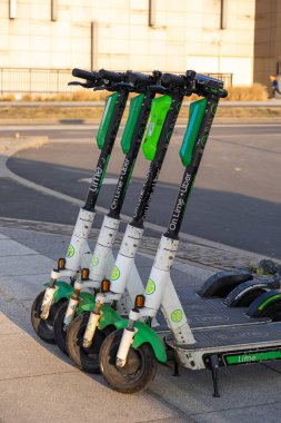 Poznan, Polonya - 22 Mart 2025: Şehir kaldırımında park halindeki Lime elektrikli scooterlar, modern metropol bölgesinde kısa mesafe seyahat için elverişli ve çevre dostu şehir ulaşımı