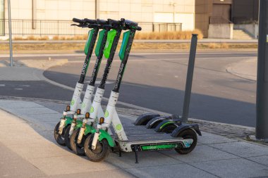 Poznan, Polonya - 22 Mart 2025: Çevre dostu Lime elektrikli scooterlar kentsel mikromobilite paylaşımı ve günlük banliyö yolcuları için modern sürdürülebilir ulaşım çözümü için şehir sokak kaldırımına park edildi