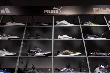 Poznan, Polonya - 22 Mart 2025: Puma Fila ve Adidas markalarından spor ayakkabıları modern spor ayakkabıları mağazasında koyu renkli iç aydınlatma ile şık raflarda sergilenmektedir.