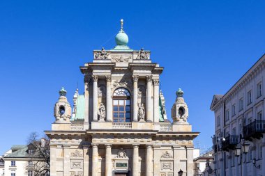 Varşova, Polonya - 3 Nisan 2025: Varşova, Polonya 'daki St. Anne Kilisesi' nin barok cephesinin karmaşık taş oymaları, uzun sütunlar, yeşil kubbeler ve parlak mavi gökyüzü