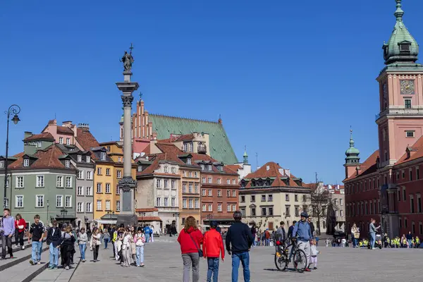 Varşova, Polonya - 3 Nisan 2025: Polonya, Varşova 'daki Castle Square' de yoğun bir gün, insanların canlı tarihi binalar, ikonik Sigismunds Sütunu ve Kraliyet Kalesi Kulesi arasında gezindiği. 