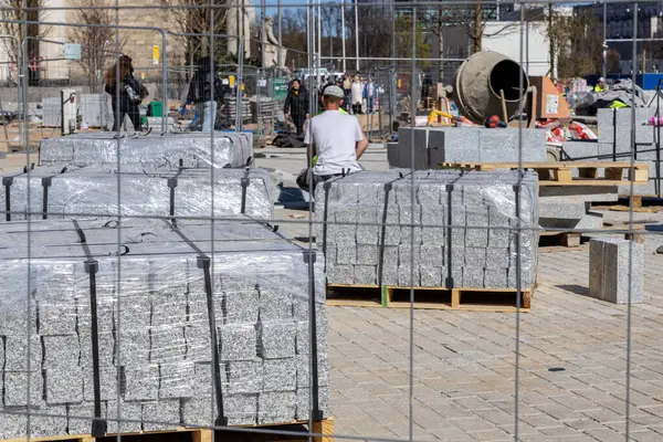 Varşova, Polonya - 3 Nisan 2025: Paletlere, görünür işçilere, eskrime ve çimento karıştırıcısına sarılı kaldırım taşları olan şehir şantiyesi. Sahne kamu alanının yeniden geliştirilmesini gösteriyor