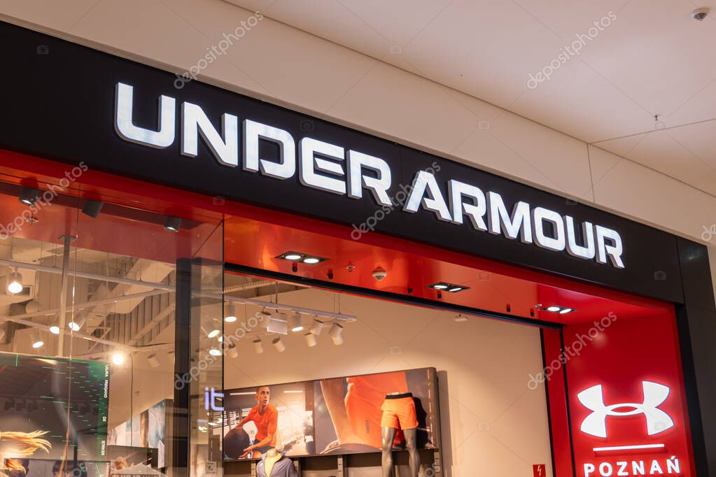 Poznan, Poland - March 22, 2025: Under Armour sportswear store front in modern shopping mall with illuminated logo and mannequins showcasing athletic clothing and training gear