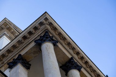Korint sütunları ve zengin dekore edilmiş bir antabatanın yer aldığı klasik bir binanın mimari ayrıntıları. Alttan bakıldığında açık mavi gökyüzü