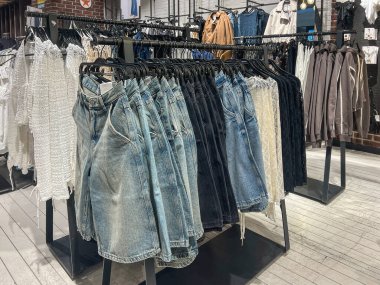 Poznan, Polonya - 2 Nisan 2025: Şık bir giyim mağazasında şık kot şortlar ve dantel etekler düzenlenir. Sergi sıradan kapüşonlular, ceketler ve üstlerle çevrili.