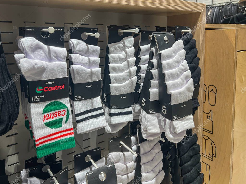 Poznan, Poland - April 02, 2025: Various styles of socks including plain white, black, striped, and branded Castrol designs are organized on display hooks in a modern retail fashion store