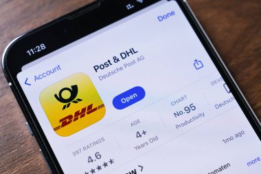 Poznan, Polonya - 26 Mart 2025: App Store 'daki Post & DHL uygulama sayfasını canlı sarı logo, açık düğme, üretkenlik kategorisi, yıldız notu ve yaş tavsiyesi içeren akıllı telefon