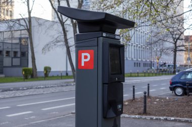 Şehir kaldırımında dokunmatik ekranı ve kart terminali olan çağdaş park ödeme makinesi, kırmızı bir P sembolü var ve şehir caddesi ve ofis binalarıyla çevrili.. 