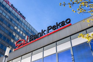 Poznan, Polonya - 8 Nisan 2025: Pekao Bankası logosu ve tabelaları yansıtıcı cam pencereler ve açık mavi gökyüzü ile çağdaş bir ofis binasında sergileniyor