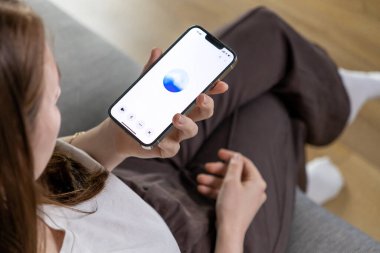 Poznan, Polonya 14 Nisan 2025: Genç bir kadın GPT tabanlı bir ses asistanıyla etkileşime geçmek için akıllı telefon kullanıyor, bu da modern yapay zeka teknolojisini günlük kullanımda gösteriyor 