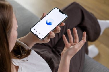 Poznan, Polonya 14 Nisan 2025: Bir kadın akıllı telefonuyla GPT ses asistanıyla iletişim kurarak günlük hayatta yapay zekanın nasıl kullanıldığını gösteriyor 