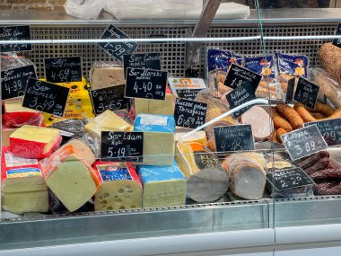 Poznan, Polonya - 18 Nisan 2025: Taze peynir, sosis ve işlenmiş et ürünlerinin bir markette veya markette soğutulmuş cam tezgahta düzgünce düzenlenmesi