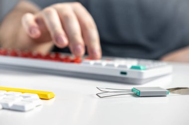 Mekanik bir klavyenin yanındaki ellerin görüntüsünü bir anahtarlık çekici ve teknolojik özelleştirme ve DIY sürecini gösteren fazladan tuş kapakları ile kapat