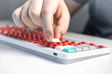 Bir kişinin mekanik bir klavyeye kırmızı düğmeli bir anahtar kapağı yerleştirmesi, DIY montajı, hassasiyet zanaatkarlığı, dokunsal geribildirim ve kişiselleştirilmiş teknoloji donanımı vurgulanması.
