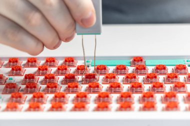 Özel bir klavye modifikasyonunda sıcak takas sürecini gösteren ve klavyeden kırmızı mekanik anahtarı ayıran kişinin makro görüntüsü