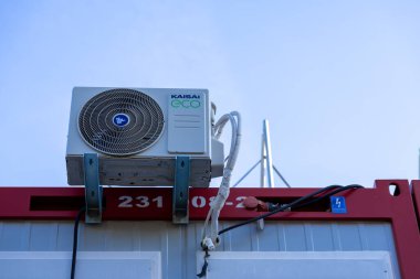 Poznan, Polonya - 30 Nisan 2025: Bir KAISAI eko klima ünitesinin görünür markalaşma, ızgarada merkezi logo ve kırmızı modüler konteynır segmentinin üstündeki bağlantı borularının detaylı görünümü