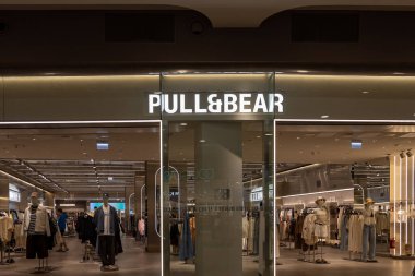 Poznan, Polonya - 30 Nisan 2025: Marka logosu bulunan PullBear mağazasının girişine bakın, mankenler ve raflar üzerinde güncel giysiler sergileniyor