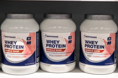 Poznan, Polonya - 30 Nisan 2025: Birden fazla vücut kütlesi olan Whey Protein Kas Kütlesi Çilek Lezzet kapları bir mağaza rafında sergilenmekte, protein takviye seçeneklerini temsil etmektedir