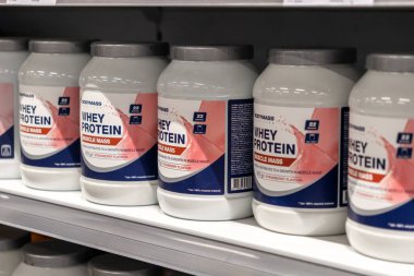 Poznan, Polonya - 30 Nisan 2025: Mevcut protein takviyelerini temsil eden bir mağaza rafında birlikte sergilenen Vücut Kütlesi Whey Protein Kas Kütlesi Çilek Lezzeti kapları