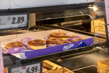 Poznan, Polonya - 30 Nisan 2025: Süpermarket fırın vitrininde sunulan lezzetli Milka çikolatalı çöreklerinin yakın çekimi, dürtülerle satın alınabilecek popüler tatlı ikramların altını çiziyor