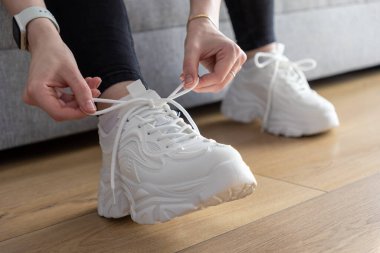 Modern tıknaz spor ayakkabılarının beyaz ayakkabı bağcıklarını korumak için ellerinizi kapatın. Günlük aktiviteler için hazır ve rahat ayakkabı seçimlerini temsil ediyor.