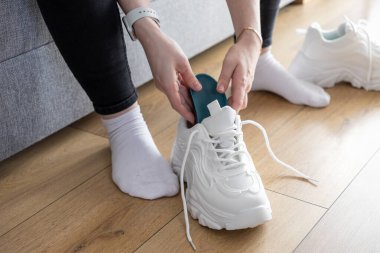 Modern spor ayakkabılarının içine mavi taban yerleştirerek, rahat spor aktiviteleri için ayakkabıları kişiselleştirmenin rutinini gösteren ellerinizi kapatın.