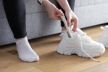 Spor ayakkabılarını korumak için kişisel rutinlerini gösteren beyaz ayakkabı şekillendiricisini kapalı alanlara yerleştiren eller.