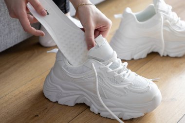 Spor ve konforu geliştirmek için kişisel rutini temsil eden, kapalı alandaki tıknaz spor ayakkabılarına beyaz taban yerleştirme