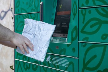 Poznan, Polonya - 25 Nisan 2025: Paketi bir Allegro paket dolabına sokan bir elin yakın plan görüntüsü, uygun e-ticaret alışverişleri için otomatik toplama noktası sistemini vurguluyor