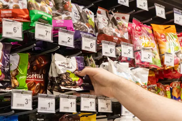 Poznan, Polonya - 25 Nisan 2025: Perakende satış rafında çeşitli şeker ve markaların sergilendiği Jutrzenka paketine uzanmak