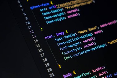 Renkli kod parçacıkları içeren koyu arkaplan içeren bir monitörün yakın plan görüntüsü, etkin bir programlama oturumu veya genel kodlama arayüzü göstergesi