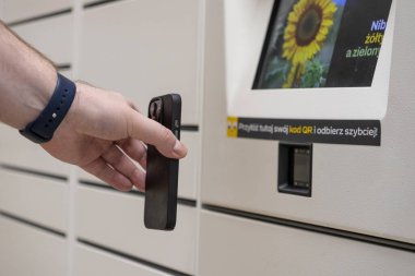 Otomatik paket koleksiyonunun modern verimliliğini gösteren bir paket dolabında QR kod tarayıcısının yanında akıllı telefonu tutan ellerin yakın çekimi