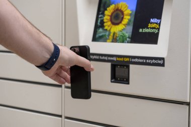 Otomatik paket koleksiyonunun modern verimliliğini gösteren bir paket dolabında QR kod tarayıcısının yanında akıllı telefonu tutan ellerin yakın çekimi