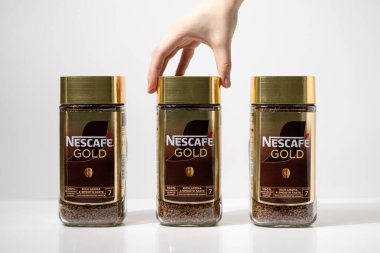 Poznan, Polonya - 2 Mayıs 2025: Nescafe altın cam kavanozları hazır kahve granülleri ve altın kapaklarla dolu ve market alışverişini veya yiyecek kavramlarını resmetmeye elverişli bir tanesine uzanıyor