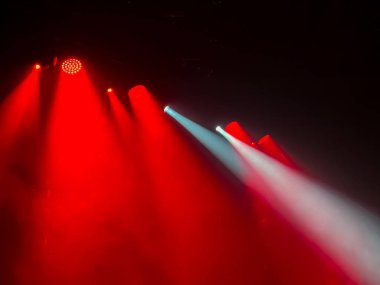 Canlı kırmızı ve beyaz sahne ışıkları karanlık mekan uzayındaki atmosferik sisi delip geçerek konserler, partiler ve canlı etkinlikler için heyecan verici bir arka plan etkisi yaratıyor.