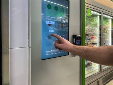 Poznan, Polonya - 23 Nisan 2025: Dokunmatik ekran self servis kiosku kullanarak otomatik alışveriş için PayPass PolCard terminali ile birlikte Lehçe metin seçer