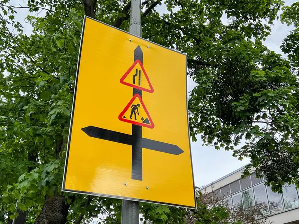 Parlak sarı geçici yol işareti, şerit ve yol çalışmalarının birleştirilmesi için gerekli trafik sapma bilgileri ve inşaat alanları için güvenlik uyarıları ileten oklarla semboller gösteriyor