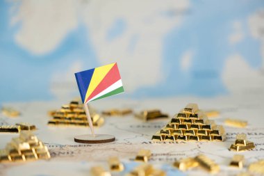 Stüdyo çekimi dünya haritasında altın külçeleriyle birlikte minyatür Seyşeller bayrağını sunarken, ulusal refah, zenginlik yönetimi ve küresel pazar varlıklarını gösteriyor