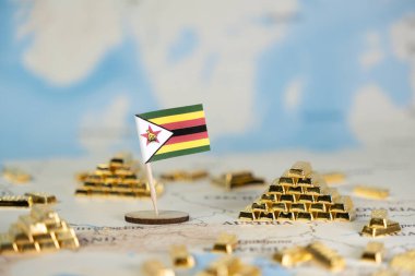 Minyatür Zimbabwe bayrağı ve pek çok parlak altın külçesi, ulusal değerli kaynaklar, ekonomik büyüme ve küresel yatırım potansiyelini sembolize eden bulanık bir dünya haritasında belirgin bir şekilde sergilenmektedir.